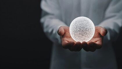 A person in a white coat holds a glowing, textured orb between their hands, set against a dark background, suggesting themes of science and innovation.