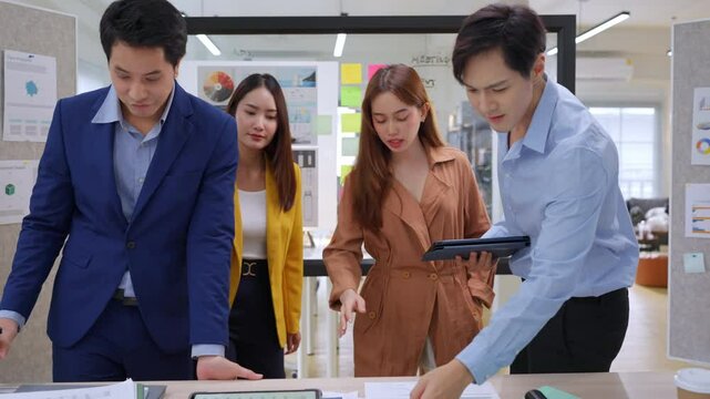 Creative Asian professionals brainstorming in a modern office. Business team collaborating on innovative ideas and strategies in a contemporary workspace, emphasizing teamwork and dynamic thinking