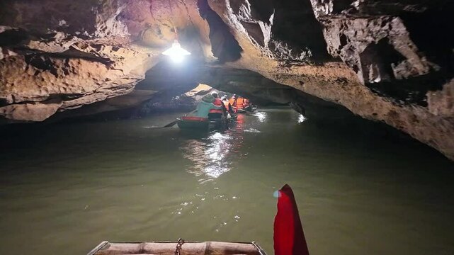  Inside view out of natural cave in Tam Coc scenic spot, Ninh Binh, Vietnam. Tourists float by boat on the river tour to grottoes. Asian natural cave