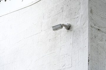 Surveillance Camera Mounted on a White Wall, Highlighting Security and Monitoring Technology for Urban Environments and Public Spaces Protection