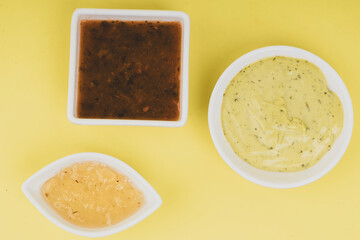 Plates with sauces for empanadas on a wooden background
