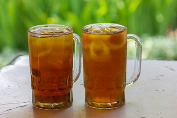 Two glasses of Iced Tea on the table with grass blurred background