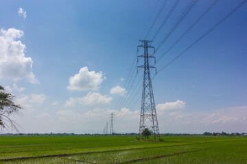View of Electric tower. High voltage electricity pylons and transmission power lines in farm field