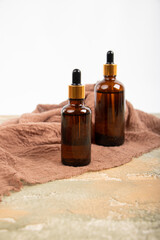 Amber Glass Dropper Bottles with Gold Caps on Rustic Fabric and Textured Surfac