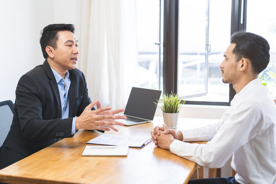Asian young manager, employer man interview with person, have question about resume and listen to candidate answer, conversation together at office. Recruitment employee job concept.