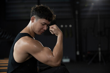 Sportsman or athlete  showing off his arm muscles in the fitness gym. Happy and positive people...