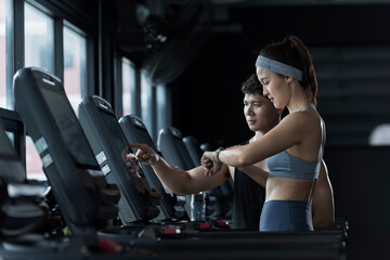 Fototapeta premium Sportswoman or athlete with trainer training while running on treadmill machine in the gym. Happy and positive people workout.