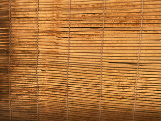 close-up of a bamboo roller blind reveals the fine, woven texture of the bamboo slats, each one featuring distinct, natural variations in color and grain. 