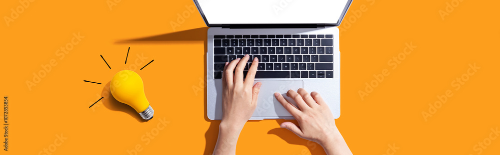 Poster person using a laptop computer and a light bulb - flat lay