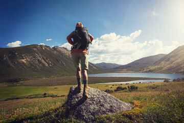 Fototapeta premium Woman hiker wearing leather boots hiking on high altitude grassland mountain top rock