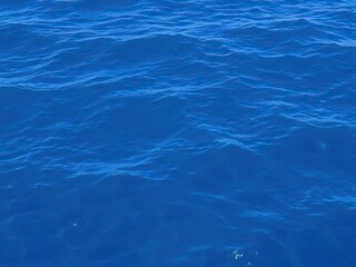 Fototapeta premium Deep blue ocean surface with gentle waves and a hint of sunlight filtering down from above, blue, movement