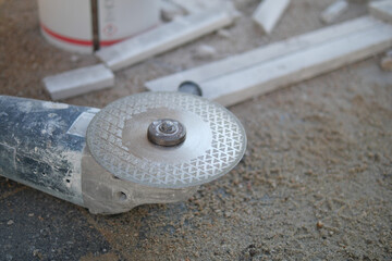 A detailed closeup view of a grinding tool resting on the floor of a workshop environment