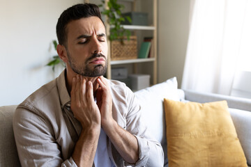 Man suffering from sore throat touching neck feeling pain. Copy space.