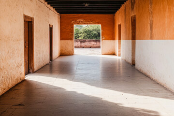 Obraz premium Sunlit corridor with warm earth tones and open doorway in historical building