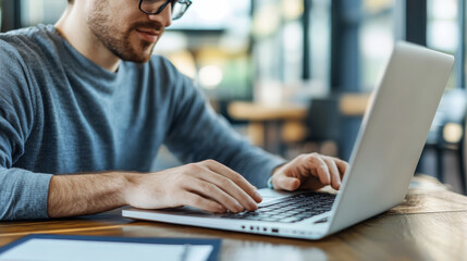 Focused on his work, man types on laptop in modern workspace, surrounded by bright and inviting atmosphere. scene captures productivity and concentration