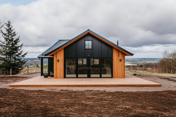 Obraz premium Modern wooden cabin in a scenic location with expansive views on an overcast day