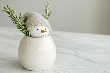 Obraz premium A charming snowman figurine with cozy hat and sprigs of rosemary peeking out from decorative vase, perfect for winter decor. This delightful piece adds festive touch to any space