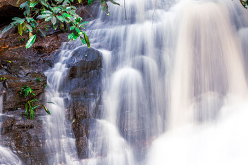 Abstract blurred background of a stream flowing rapidly from rocks in a deep forest, natural waterfalls that occur naturally during the rainy season, the completeness of the ecosystem, fresh air.