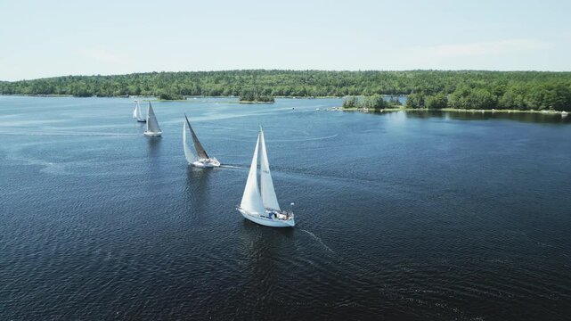 Aerial view of sailing vessels racing one another across picturesque Shelburne harbour, Nova Scotia, Canada. MAX QUAL PRORES422HQ Transcode of 4K H.265 D-CINELIKE original capture.