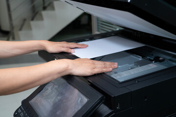 woman hands putting a sheet of paper into a copying device