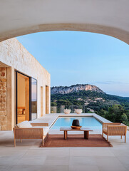 Fototapeta premium Luxurious outdoor seating area with a pool and stunning mountain view at sunset