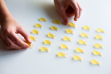 Obraz premium Hands with Fish-Shaped Omega-3 Capsules on White Background