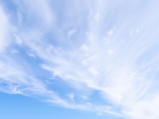 A serene landscape of a blue sky with soft, white clouds drifting lazily across the horizon, idyllic, skyward