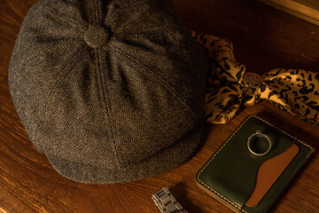 Classic newsboy cap or eight panel hat made of wool herringbone fabric on a wooden table in a dark...