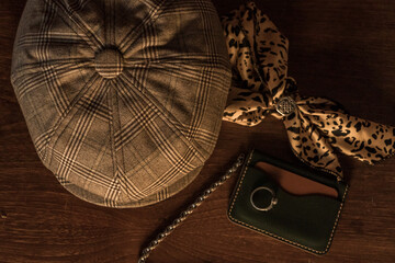 Classic newsboy cap or eight panel hat made of wool herringbone fabric on a wooden table in a dark...