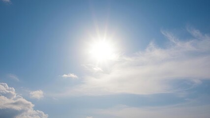Fototapeta premium Softly glowing sun peeking through wispy clouds in a serene blue sky, soft focus, gentle glow