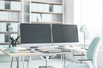 Side view on blank dark modern computer monitors on light wooden table with light blue lamp, flowerpot and chair on white floor in sunny office with big window. 3D rendering, mockup