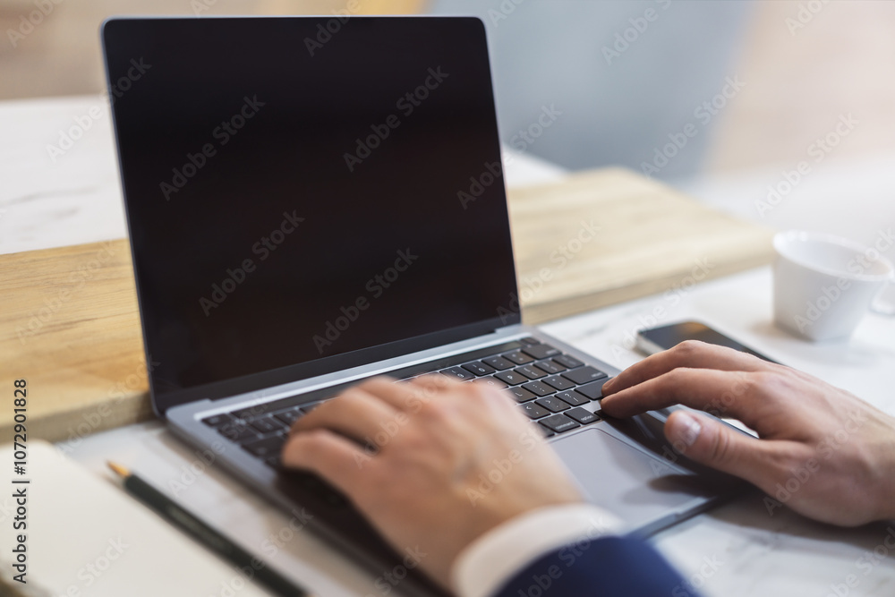 Poster The image captures a man's hands typing on a modern laptop keyboard, with the office setting in the background appearing blurred