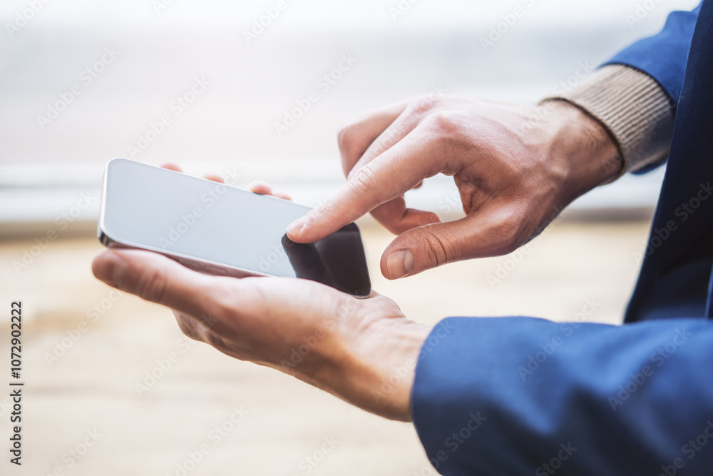 Poster man concentrated on his sleek smartphone within the soft focus of an active office environment