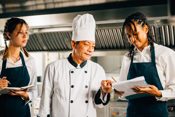 In a restaurant kitchen senior Asian chef educates multiracial students. Emphasizing teamwork...