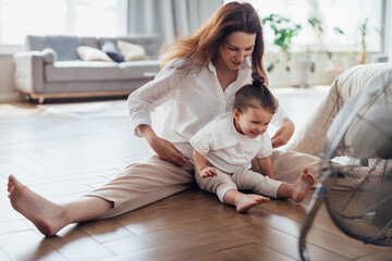 Summer heat, woman and child sitting on the floor in front of a fan