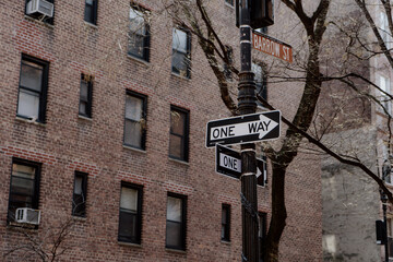 Urban street sign standing prominently against a rustic brick building in city