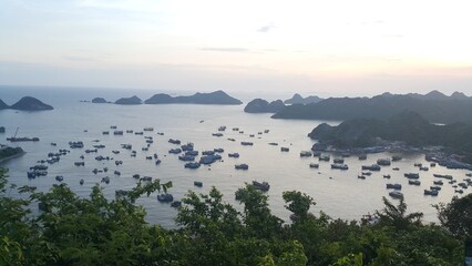 Breathtaking view of fishing boats dotting a tranquil bay surrounded by lush hills at sunset