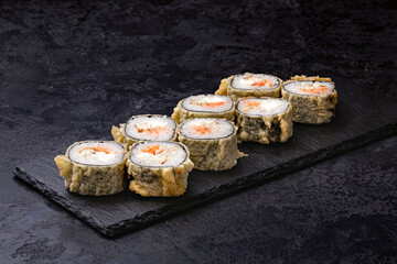 Japanese rolls, sushi fried tempura salmon and cream cheese on black background.