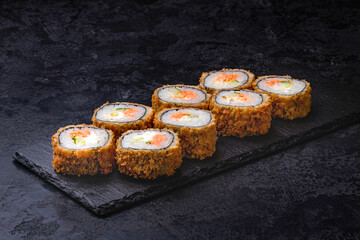 Japanese rolls, sushi fried tempura salmon and cream cheese on black background.