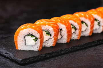 Japanese rolls, Philadelphia sushi with salmon and cream cheese on a black background.