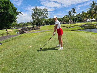 Fototapeta premium A golfer prepares to tee off at a lush tropical golf course