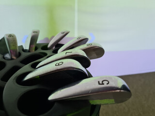 Close-up view of golf clubs arranged in a rack during an indoor golfing session