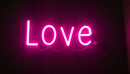 Neon pink "Love" sign on dark background for Valentine's Day