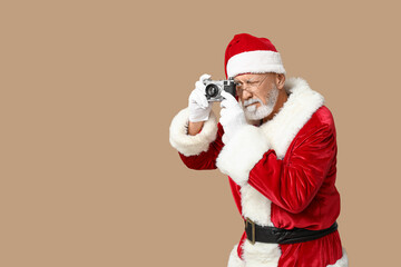 Santa Claus in glasses with camera taking photo on brown background
