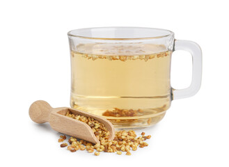 Glass cup of fresh buckwheat tea and wooden scoop on white background