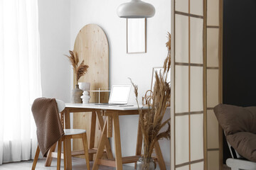 Modern workplace with laptop, home decor and folding screen