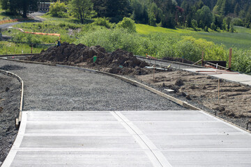 Unfinished sidewalk, partly paved, in a large suburban community.
