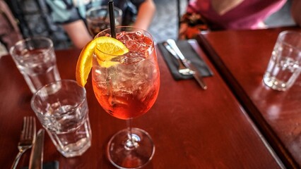 Elegant Sparkling Wine Glass with Orange Slice on a Dark Red Table Setting, Close-up View