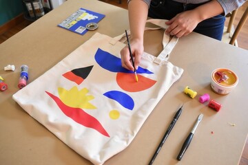 Hands painting abstract art on canvas tote bag for creative diy project
