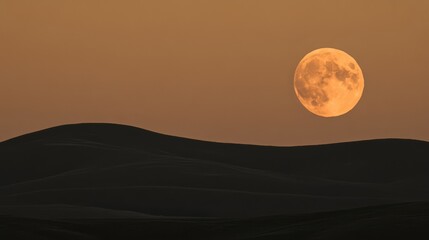 A large, full, orange moon rising over a dark, rolling desert landscape.